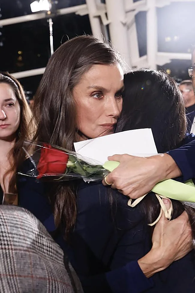 Meilingas apkabinimas tarp karalienės Letizia ir vienos iš Valensiją nusiaubusios siaubingos žalos aukų giminaičio.