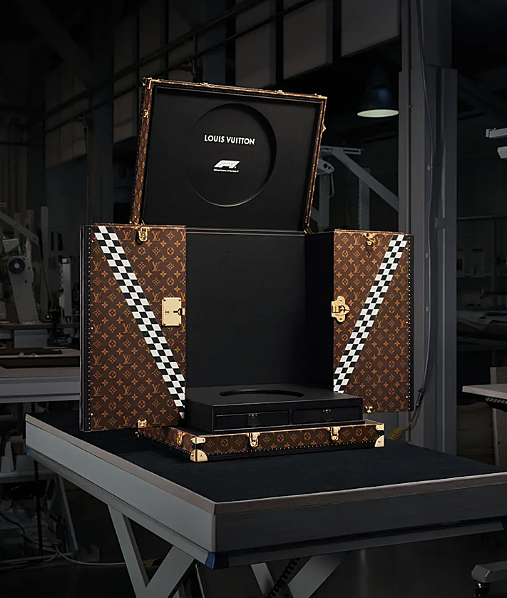 2 antrinis vaizdas – „Gucci F1“ automobilis, čekų „Pérez plyoto“, apsirengęs Tommy Hilfiger drabužiais, ir „Louis Vuitton“ bagažinė už trofėjų.